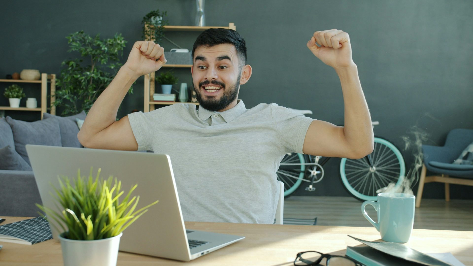Man celebrating success while working on laptop.